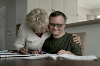 Mother hugging caucasian man with down syndrome while learning at home